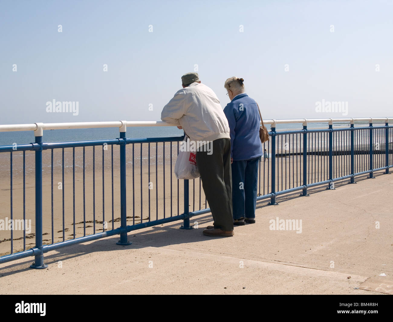 La molla al mare una coppia di anziani lean sulla rampa al sole sulla Redcar promenade Foto Stock