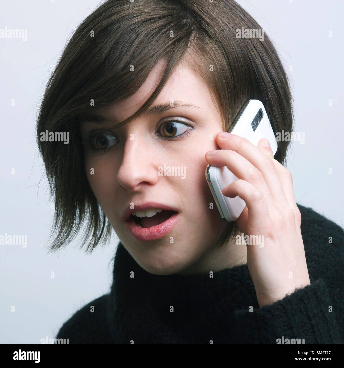 Giovane donna con una sorpresa / sconvolto l'espressione su un telefono cellulare Foto Stock