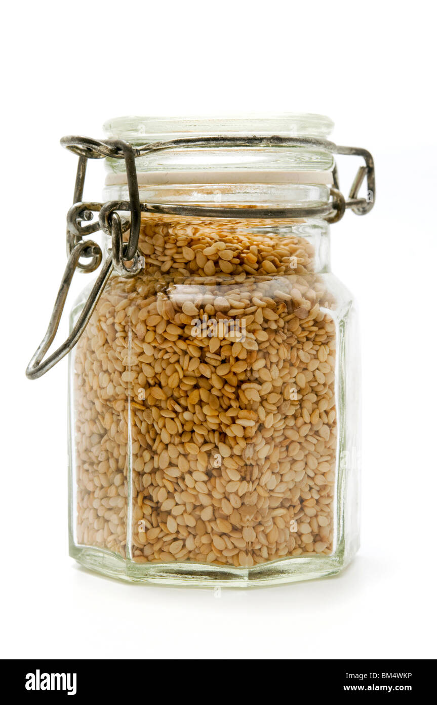 Un contenitore riempito con semi di sesamo su sfondo bianco Foto Stock