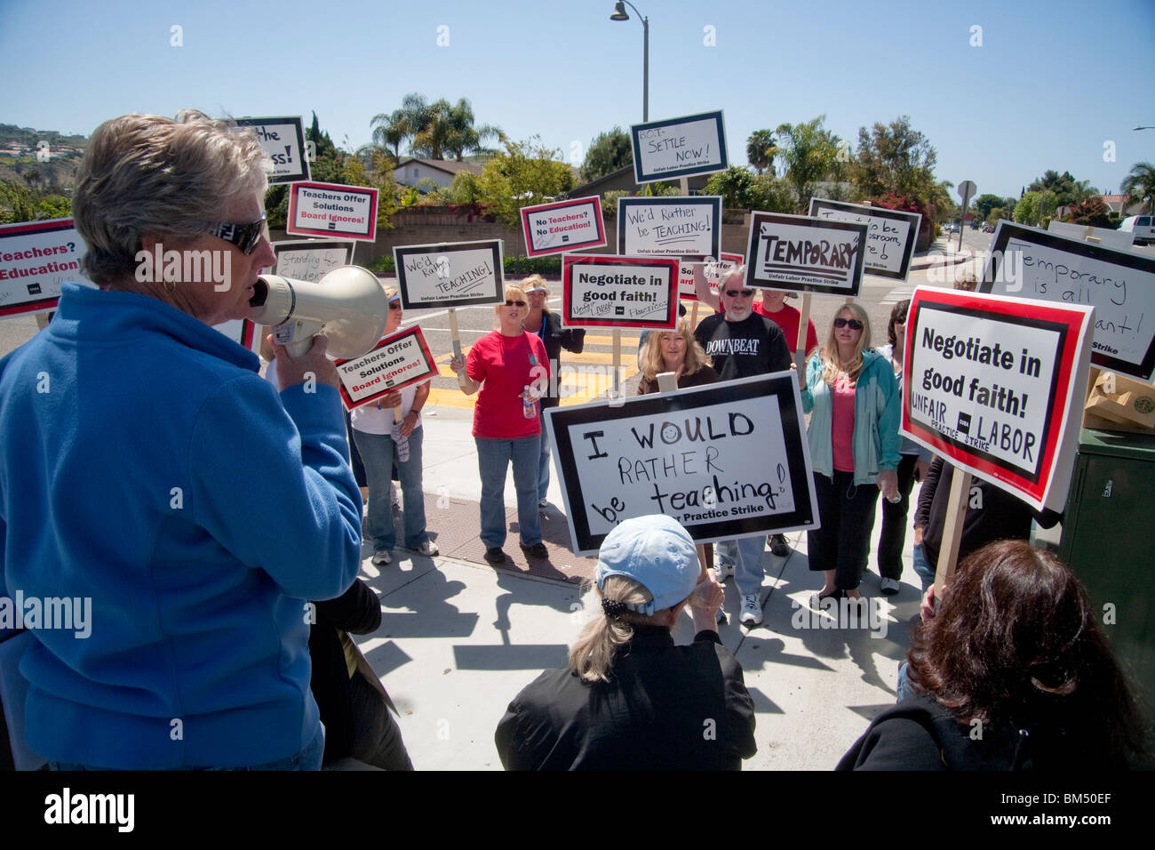Protestando proposto tagli a pagamento, colpendo gli insegnanti picket la loro scuola a San Juan Capistrano, California. Nota segni e bullhorn. Foto Stock