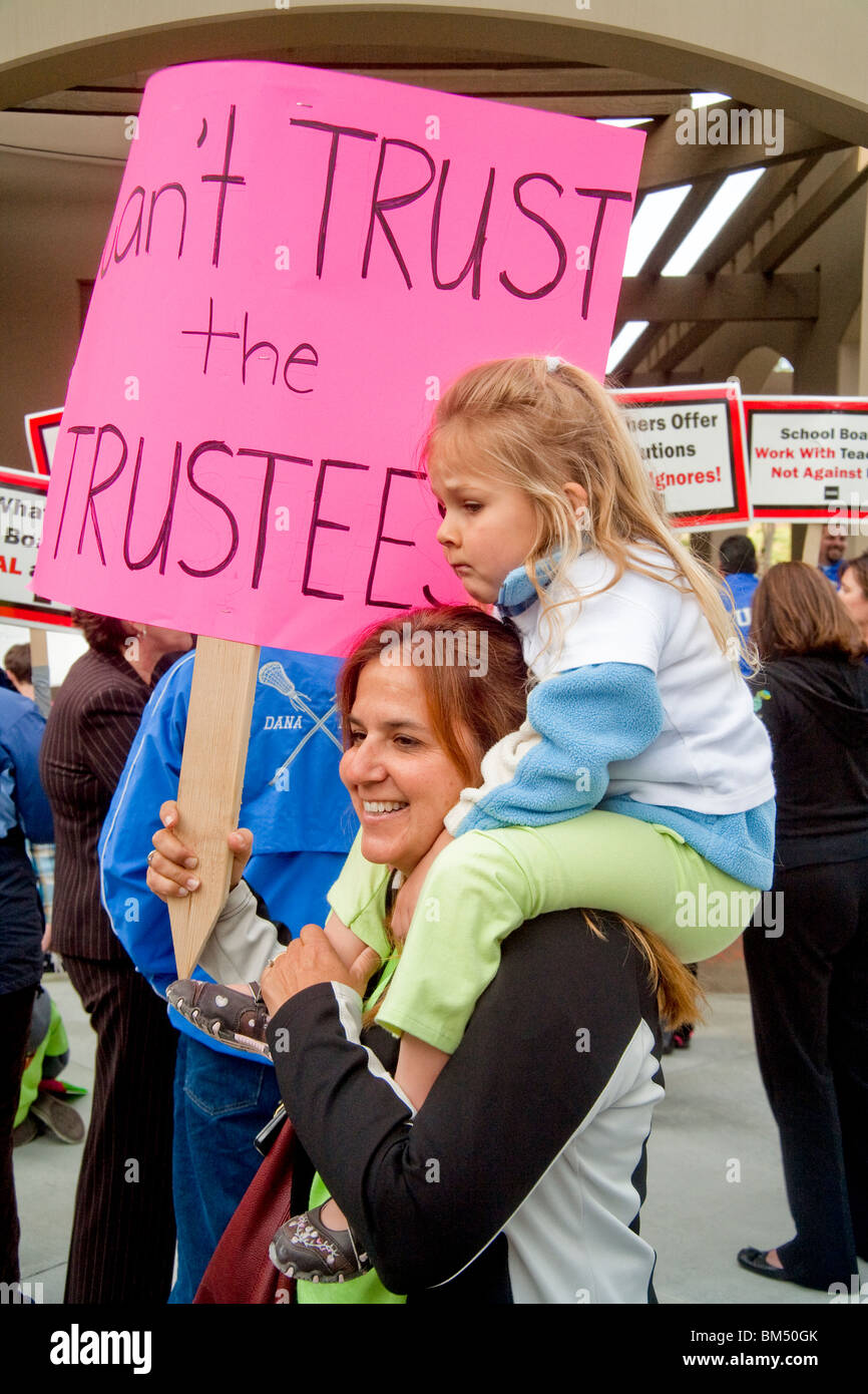 Portando un segno e suo figlio, una protesta insegnante della scuola rally su proposte di tagli dei salari in una San Juan Capistrano, CA. Foto Stock