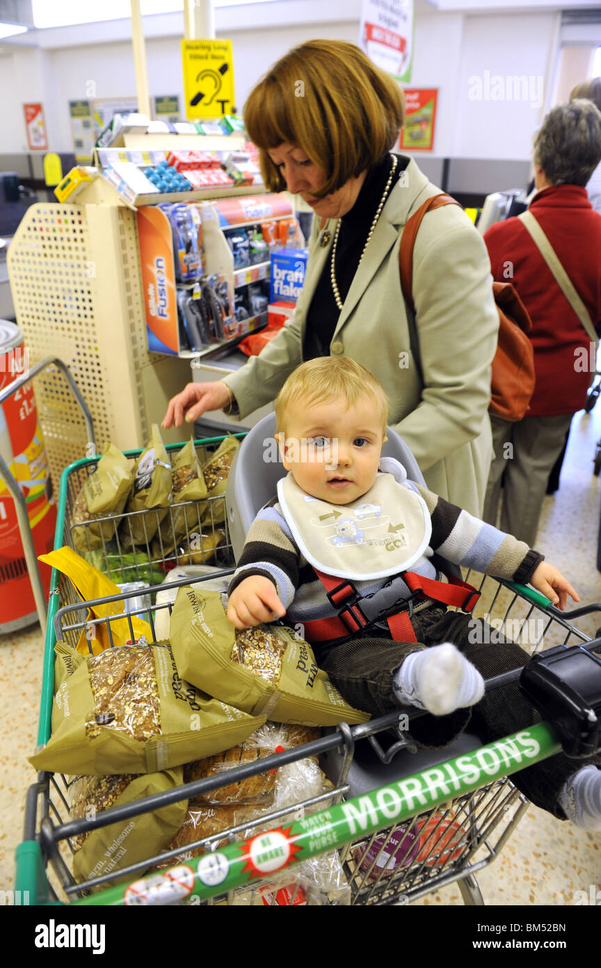 Donna che acquista con il bambino nel carrello del supermercato al momento del check-out Negozio per famiglie del Regno Unito con bambini madre e bambino 2010 Foto Stock