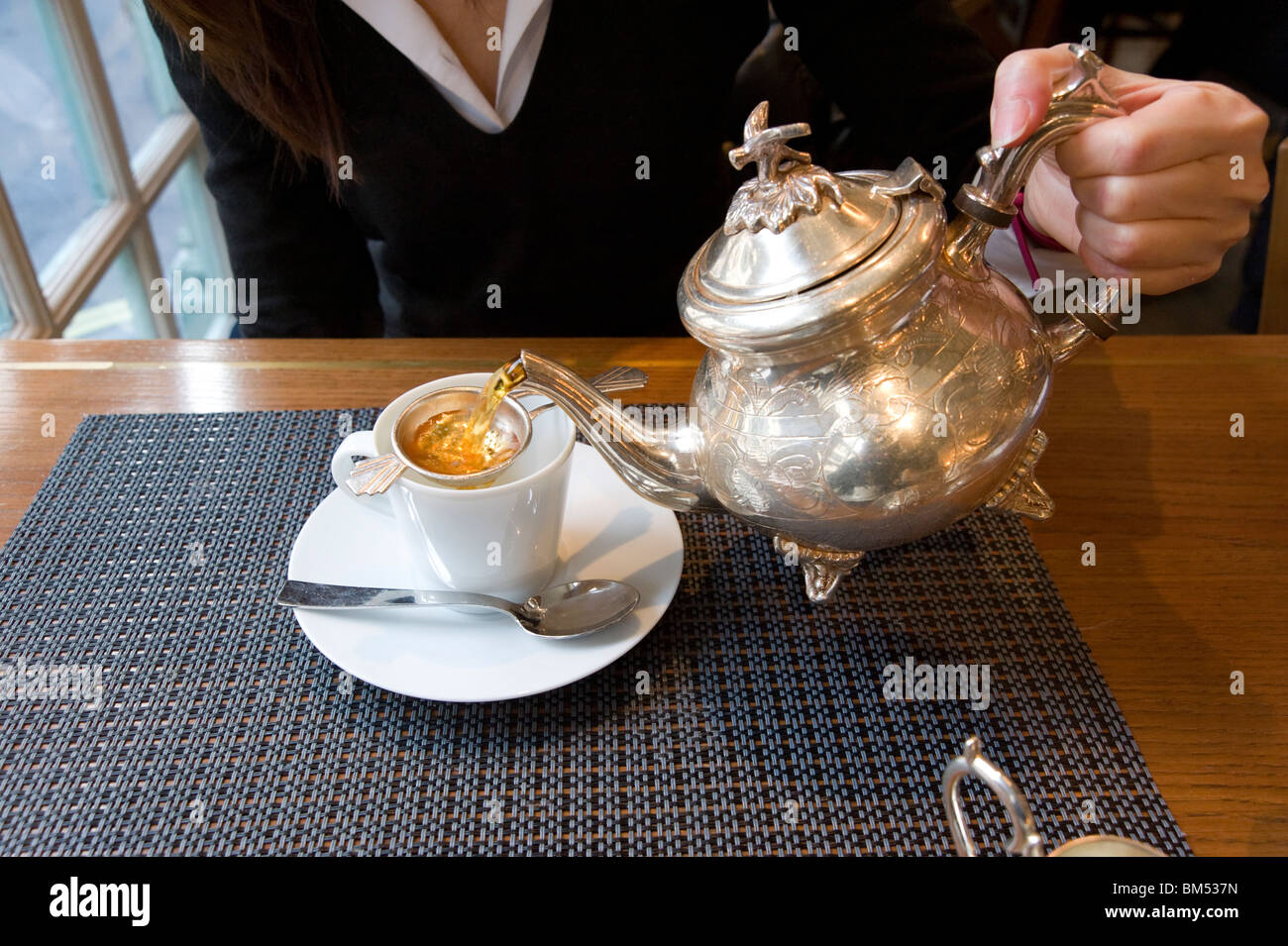Versare una tazza di tè da una teiera Louis Phillipe placcata in argento a Fortnum e Mason, Londra, Regno Unito Foto Stock