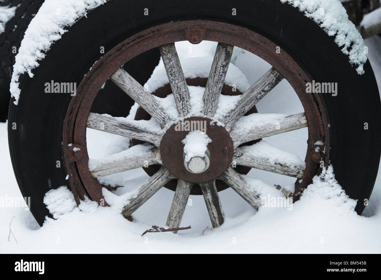 La neve copre un trattore abbandonato il carro in legno del mozzo della ruota di un veicolo antico in una fattoria in Finlandia Foto Stock