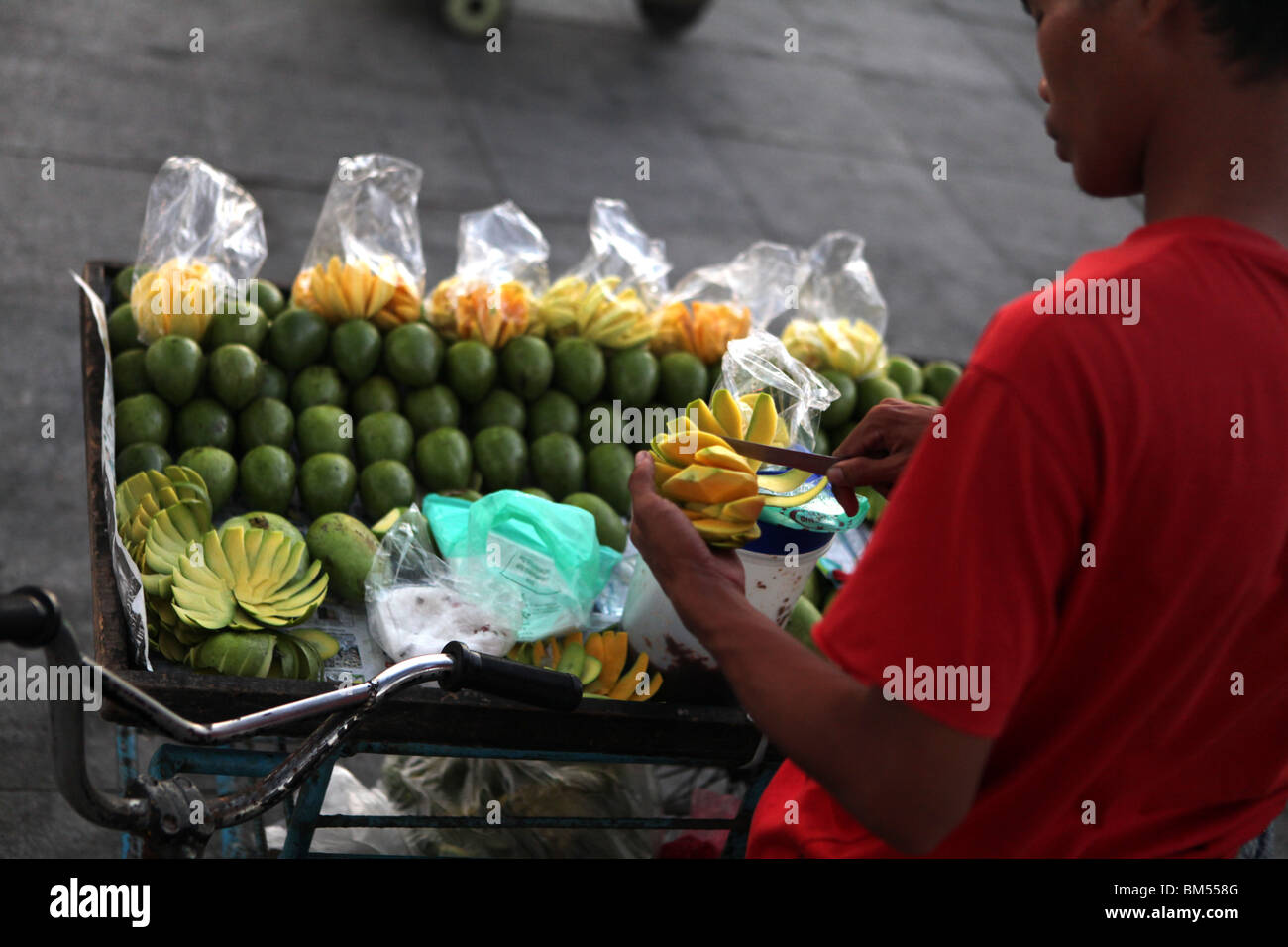 Un giovane uomo prepara il mango in Roxas Boulevard da Manila Bay nei pressi di malato in Manila, Filippine. Foto Stock