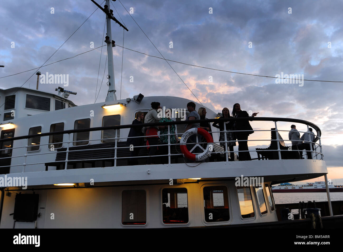 Le persone si mettono sul ponte del Mersey Ferry, Liverpool al tramonto Foto Stock