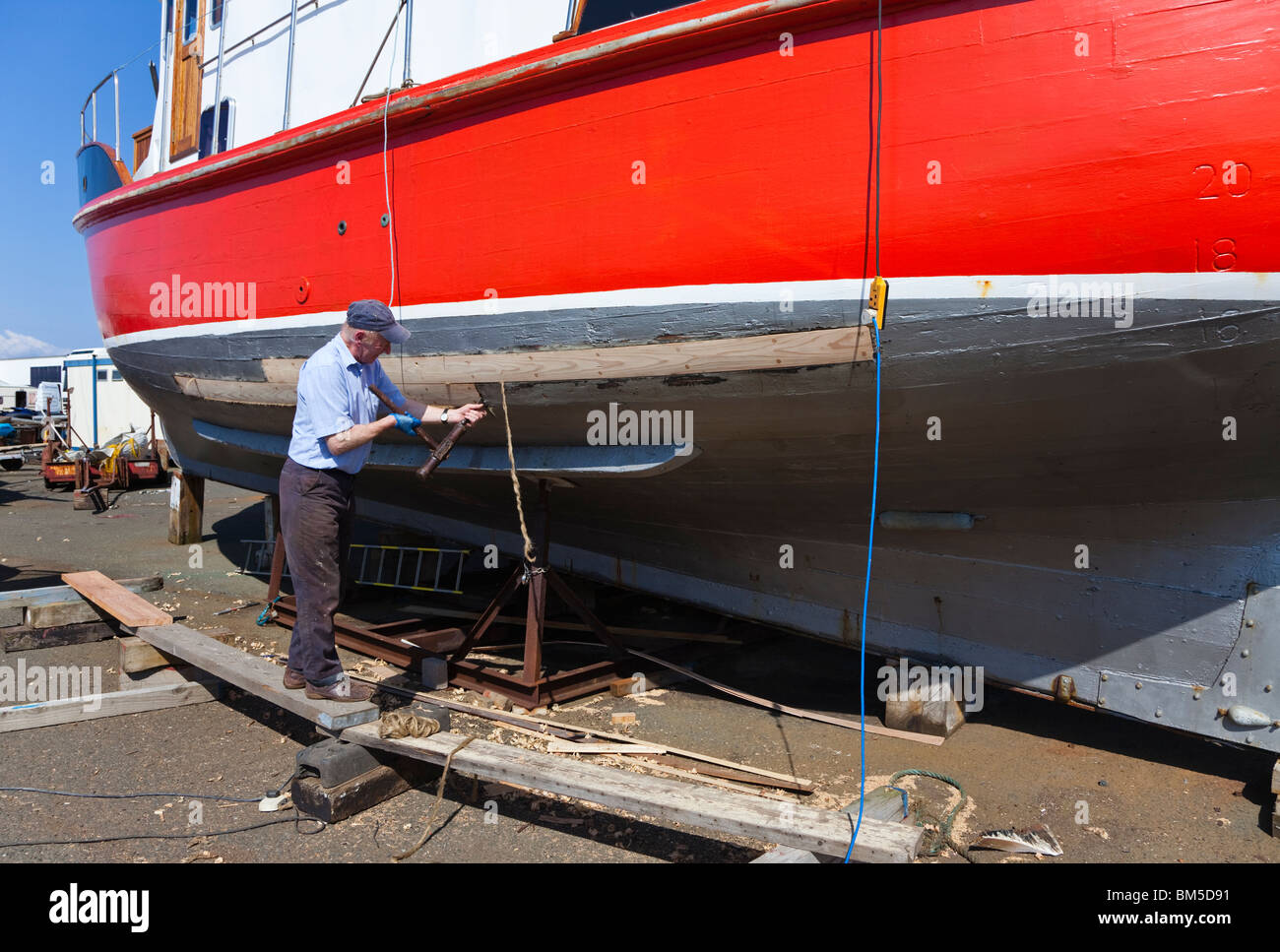 Nave Master builder, John Gaff, riparazione dello scafo di una barca da pesca con il tradizionale metodo di imballaggio oakum negli interstizi Foto Stock