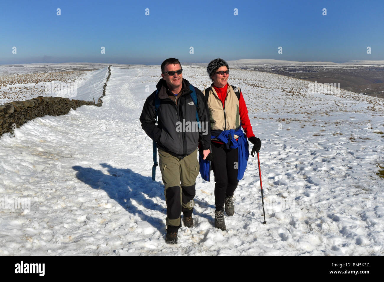 Una coppia di mezza età mantenersi in forma camminando su un luminoso giorno d'inverno. Foto Stock