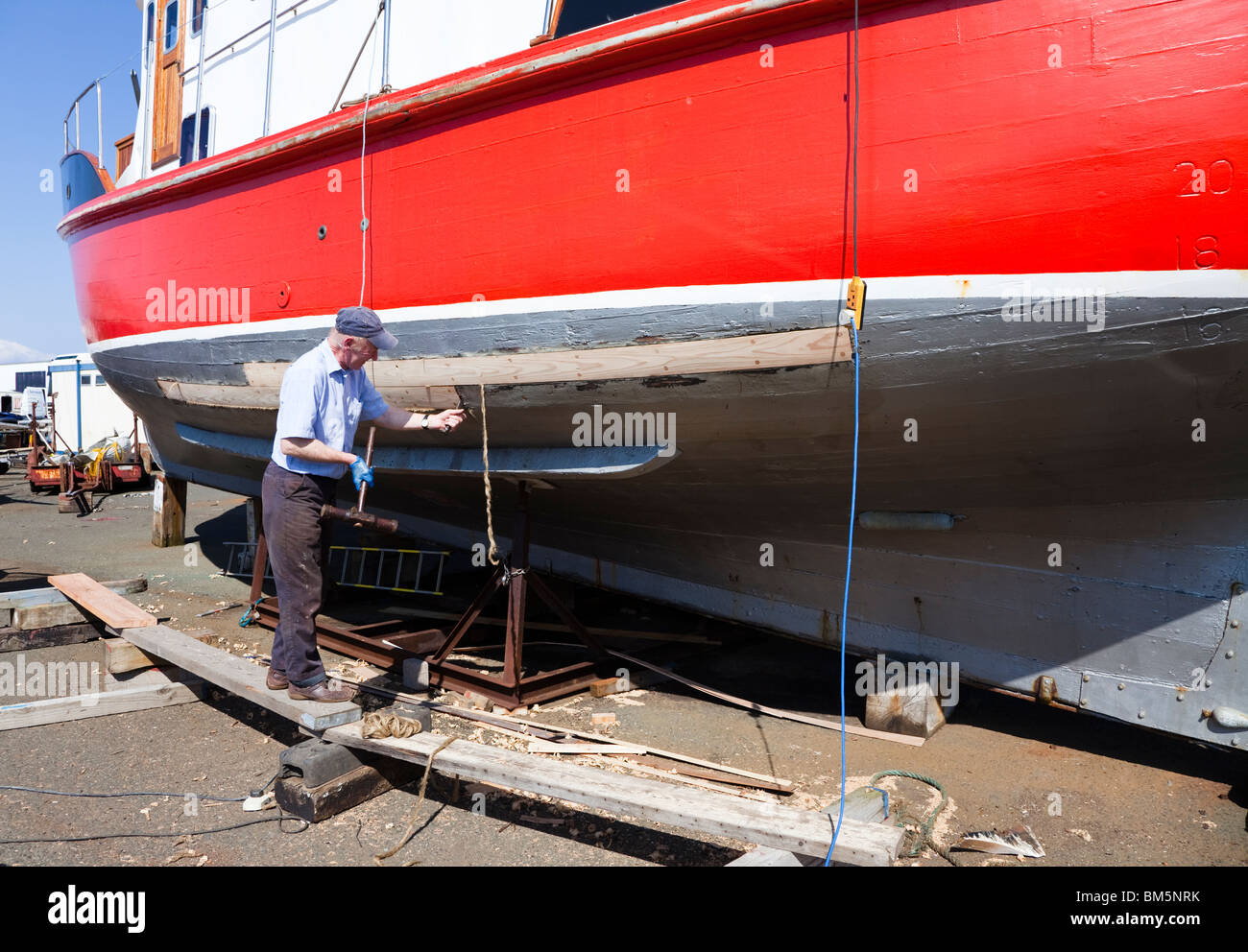Nave Master builder, John Gaff, riparazione dello scafo di una barca da pesca con il tradizionale metodo di imballaggio oakum negli interstizi Foto Stock