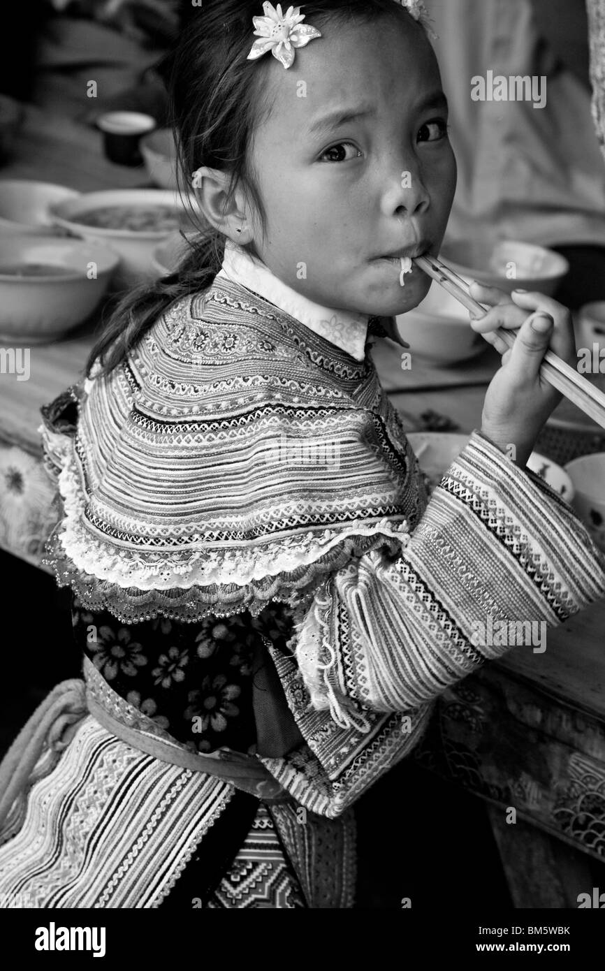 Bambino da fiore Hmong Hill Tribe, mangiare tagliatelle, Coc Li Mercato, SAPA, Vietnam Foto Stock