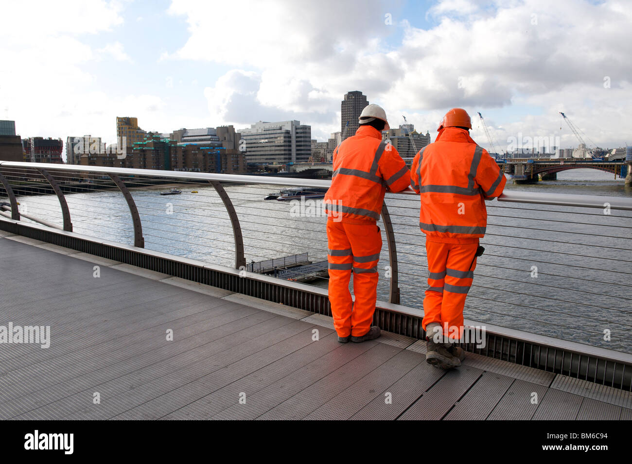 Due uomini su un ponte di Londra in giacche ad alta visibilità Foto Stock