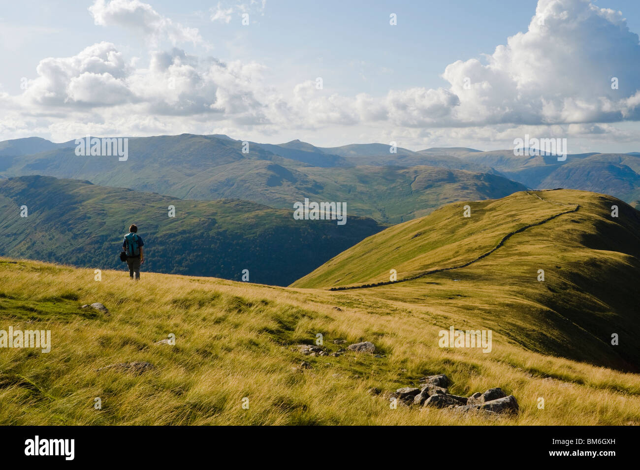 Il camminatore solitario sulla cresta sopra Hartsop Dodd, Lake District, con Helvellyn all'orizzonte Foto Stock