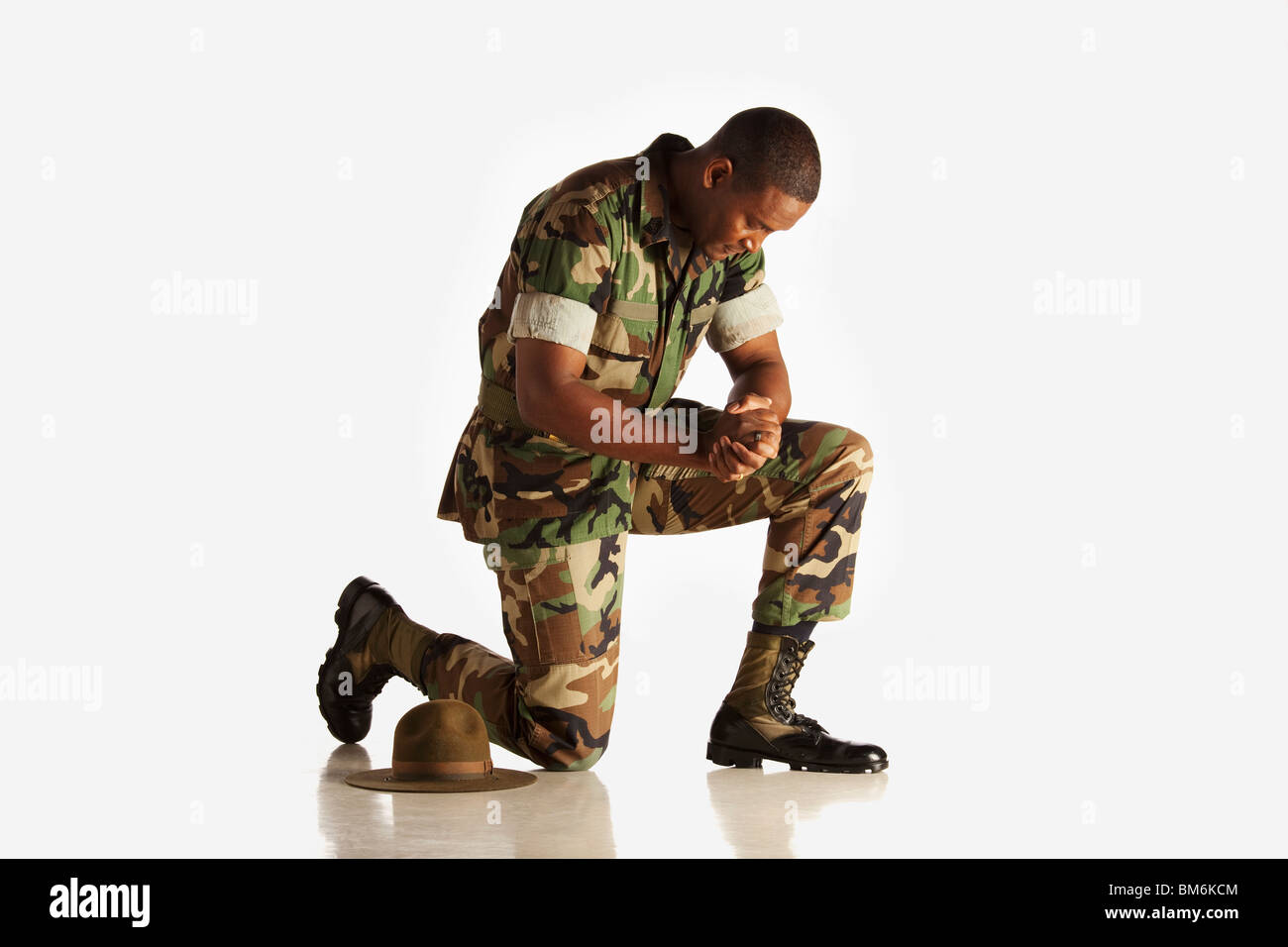 Un uomo militare inginocchiato con la sua testa piegata Foto Stock