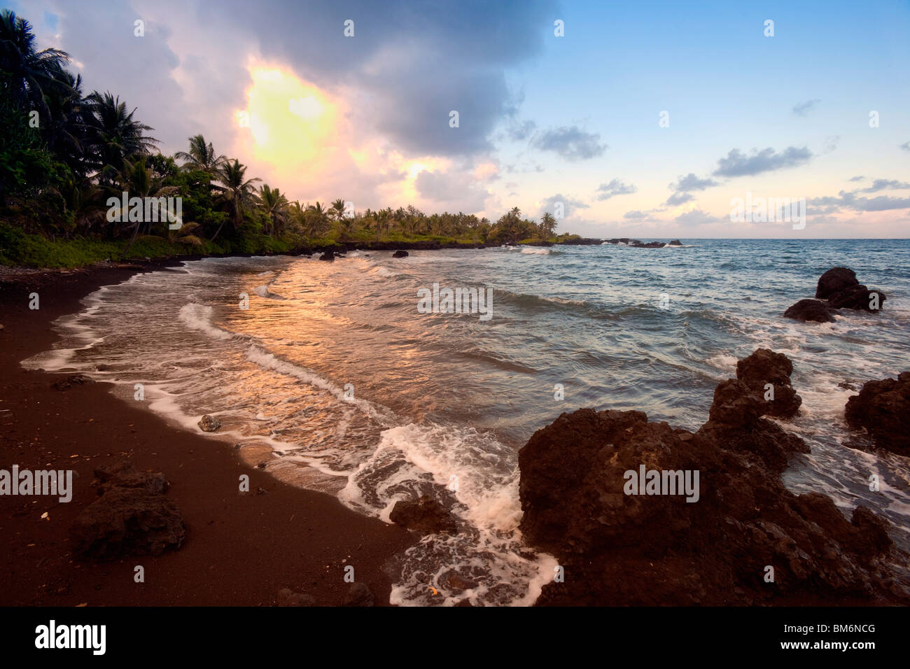 Litorale di Hana Bay a Maui al tramonto con spiaggia di sabbia nera. Foto Stock