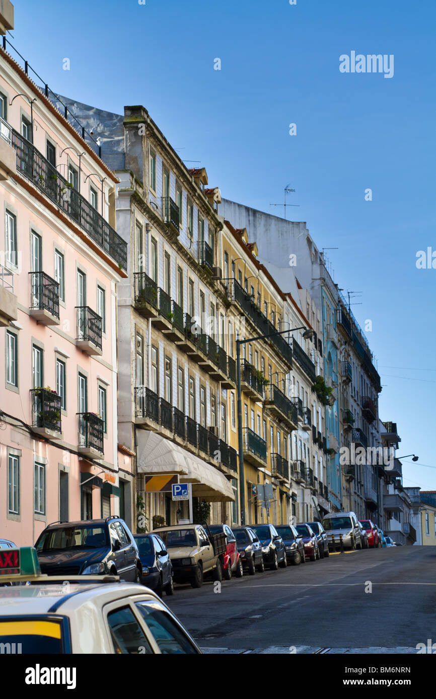 L'angolo di un taxi lungo una strada di Lisbona , con macchine parcheggiate e di vecchi edifici. Lisbona, Portogallo Foto Stock