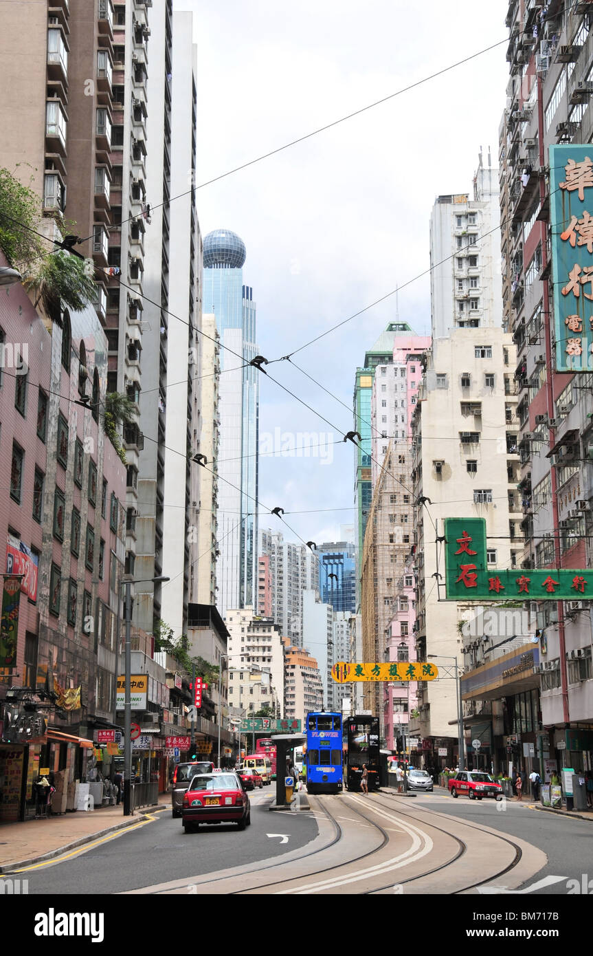 Due tram, in mezzo alla strada, al Des Voeux Road a ovest la fermata del tram, guardando ad ovest attraverso un grattacielo canyon, Hong Kong Foto Stock