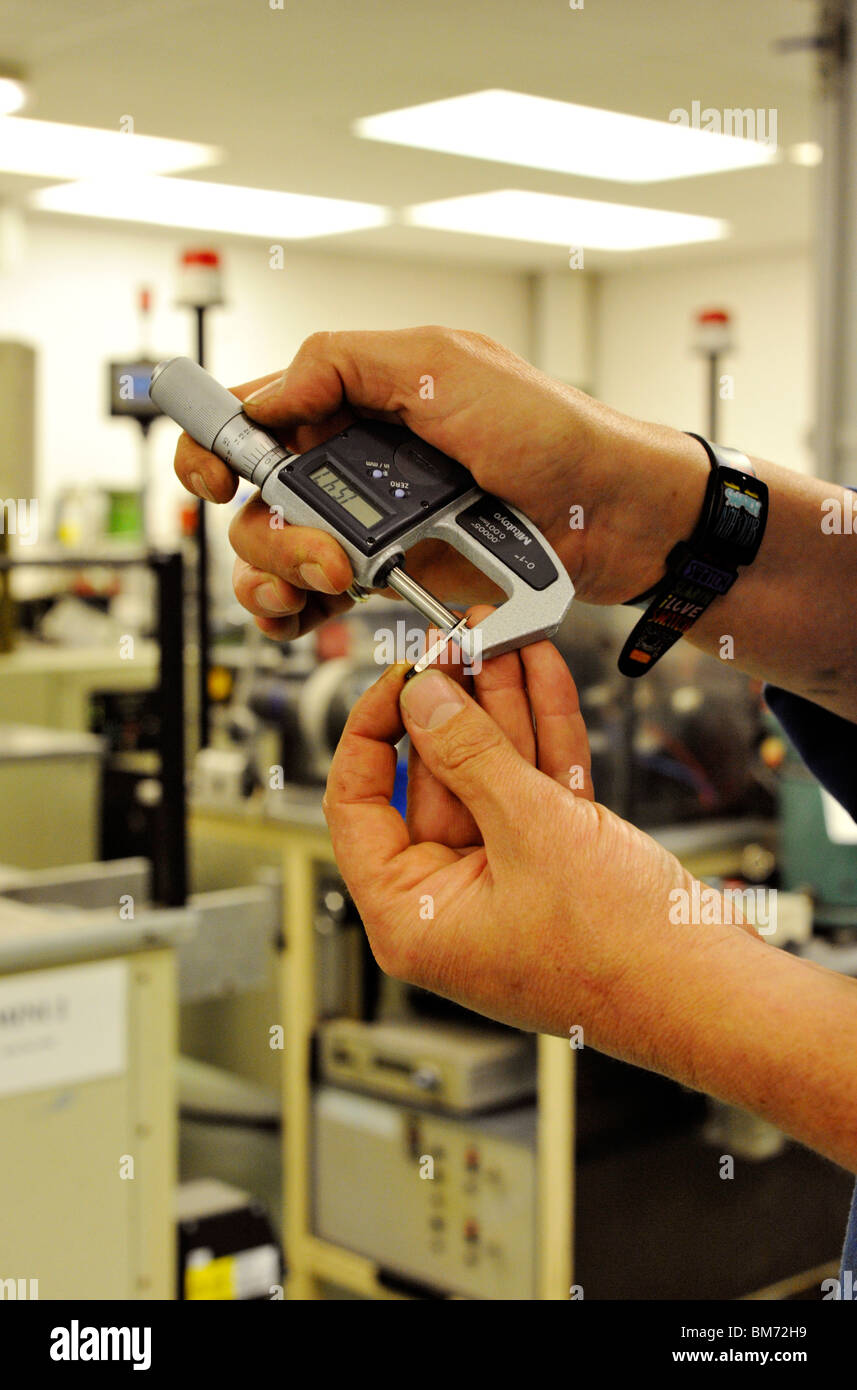 Operaio di fabbrica utilizzando il micrometro per misurazioni di controllo Foto Stock
