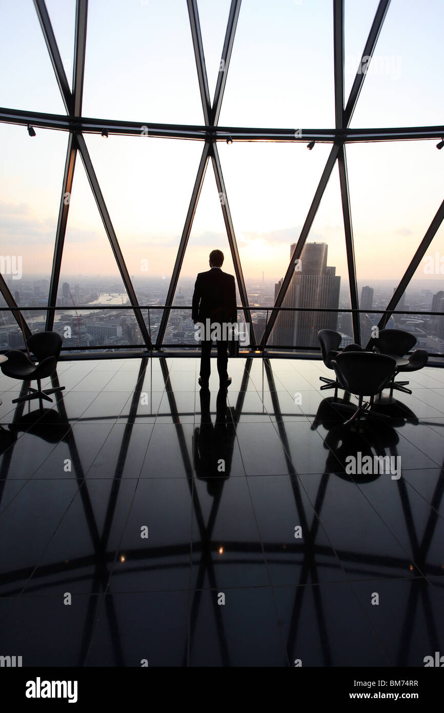 Un imprenditore stand con la sua valigetta in cima il Gherkin grattacielo nella city di Londra, Regno Unito Foto Stock