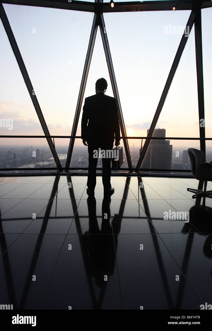 Un imprenditore stand con la sua valigetta in cima il Gherkin grattacielo nella city di Londra, Regno Unito Foto Stock