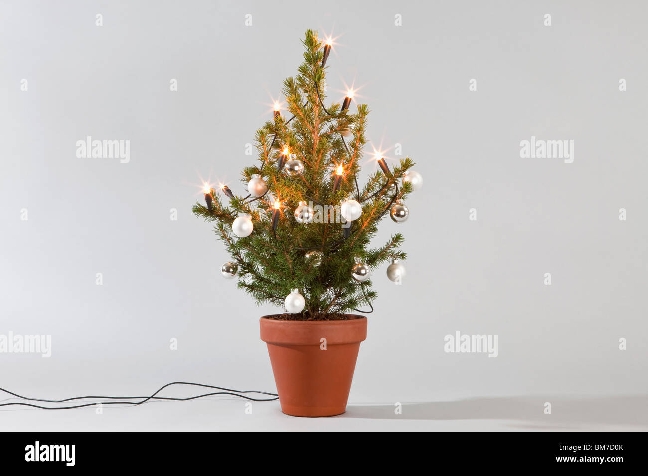 Un piccolo albero di Natale decorato con luci e baubles Foto Stock