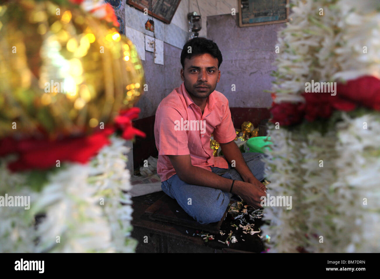 Un uomo che fa ghirlande di fiori nel mercato Devaraja a Mysore, Karnataka, India. Foto Stock