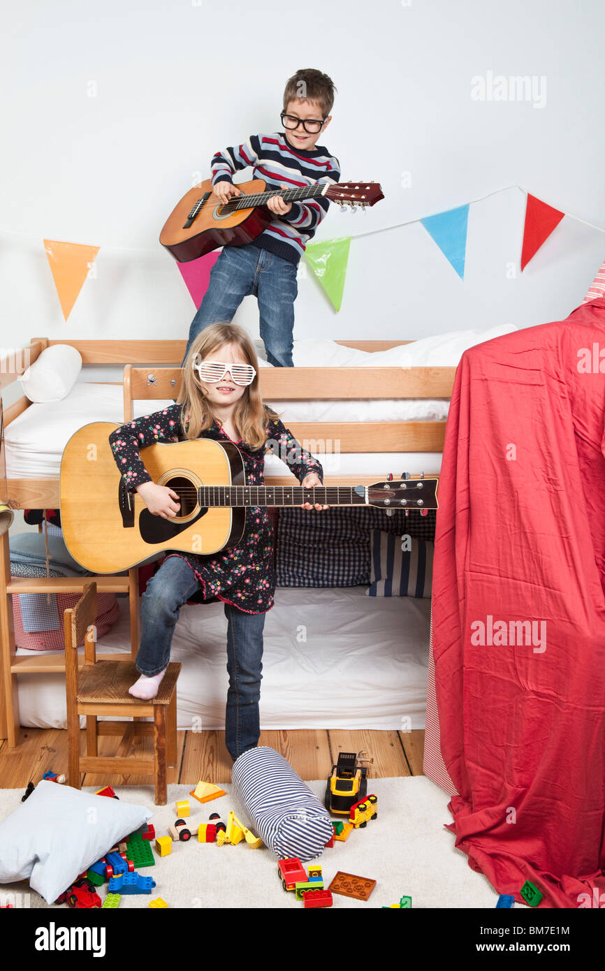 Due bambini che giocano con le chitarre del bambino in una sala giochi Foto Stock