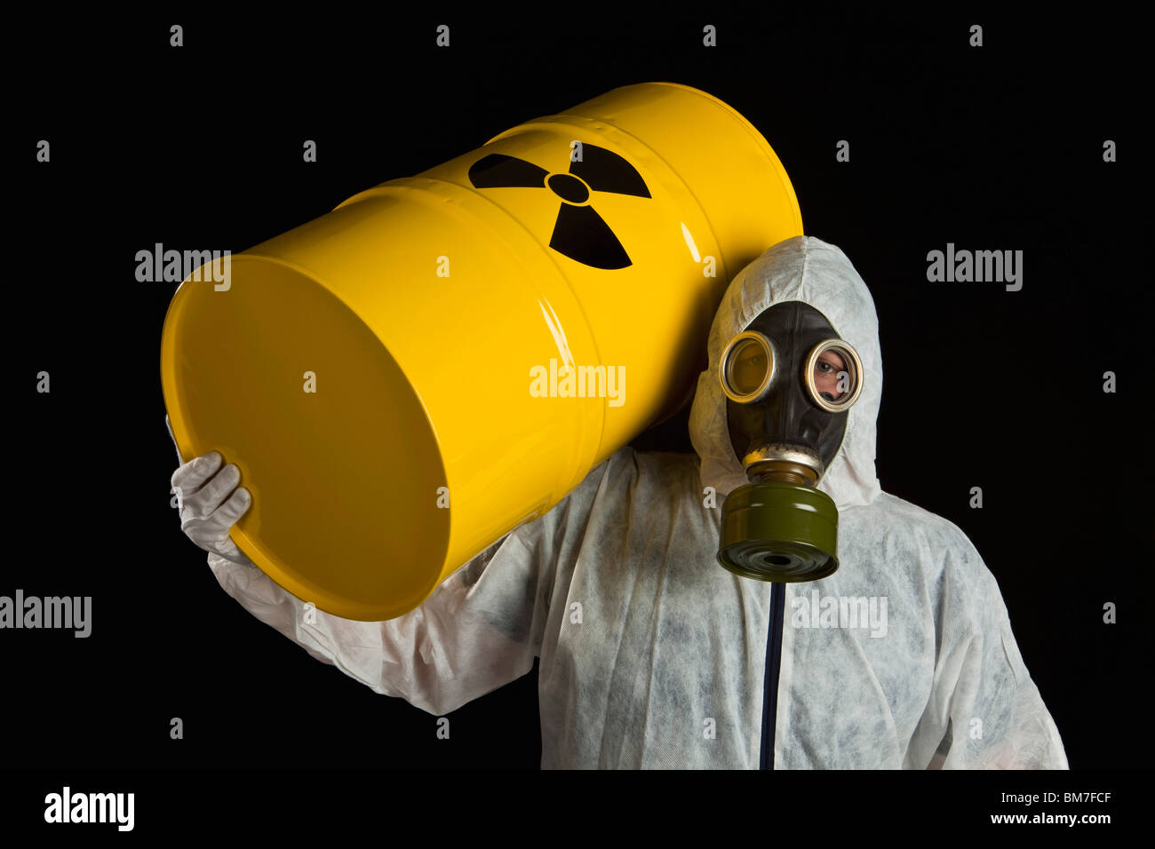 Una persona che porta un cilindro radioattivo e indossando indumenti protettivi Foto Stock
