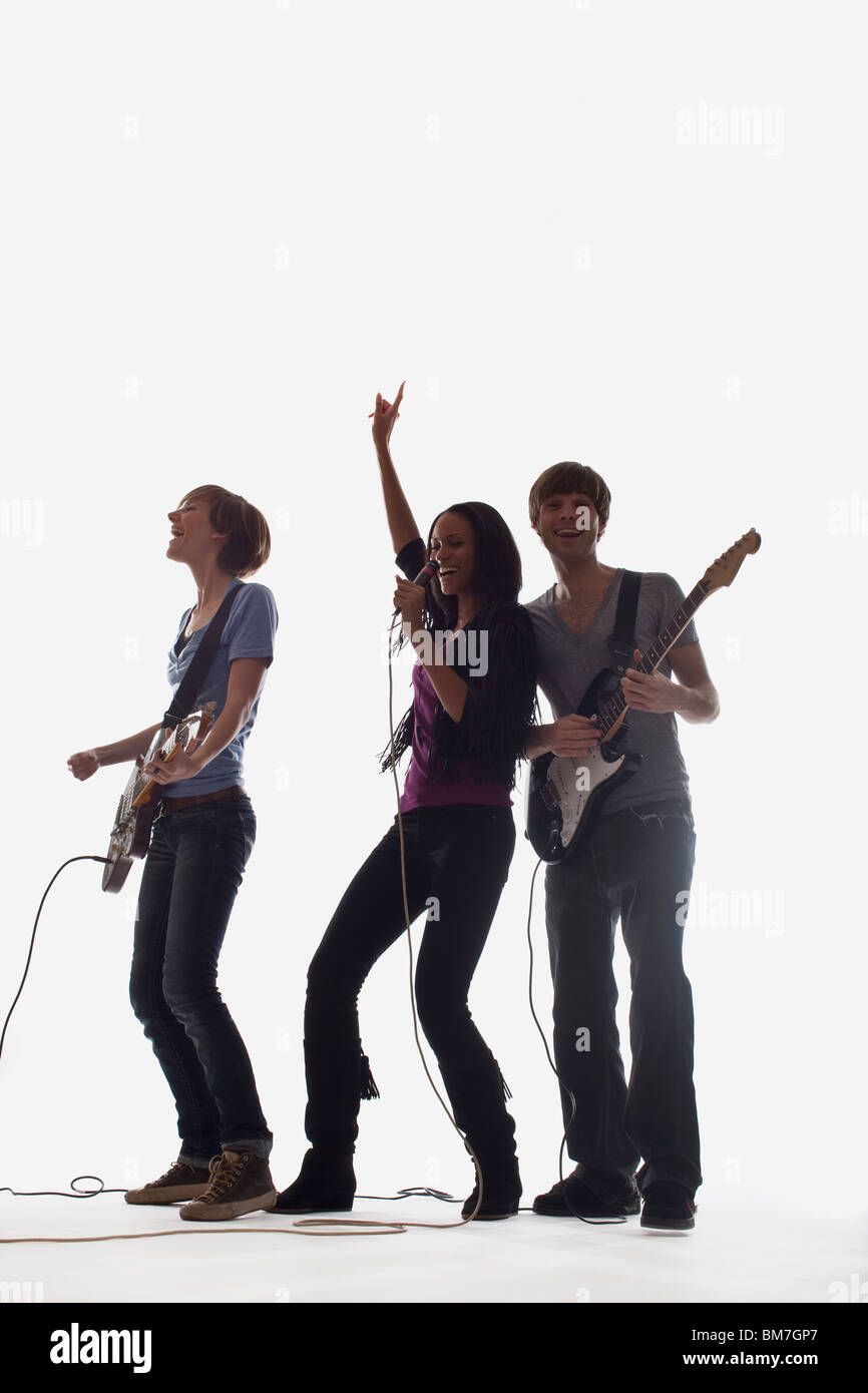 Due chitarristi e un cantante di eseguire, studio shot, sfondo bianco retroilluminato Foto Stock