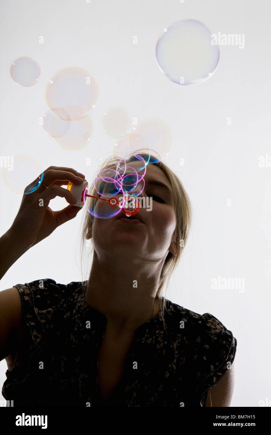 Una donna a soffiare bolle con una bacchetta di bolle Foto Stock