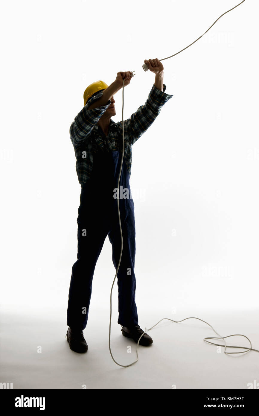 Un lavoratore edile di mettere un tappo in un cavo di prolunga Foto Stock