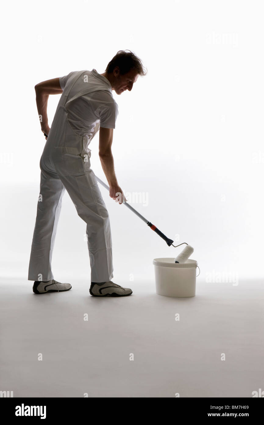 Un pittore di casa usando un rullo di vernice Foto Stock
