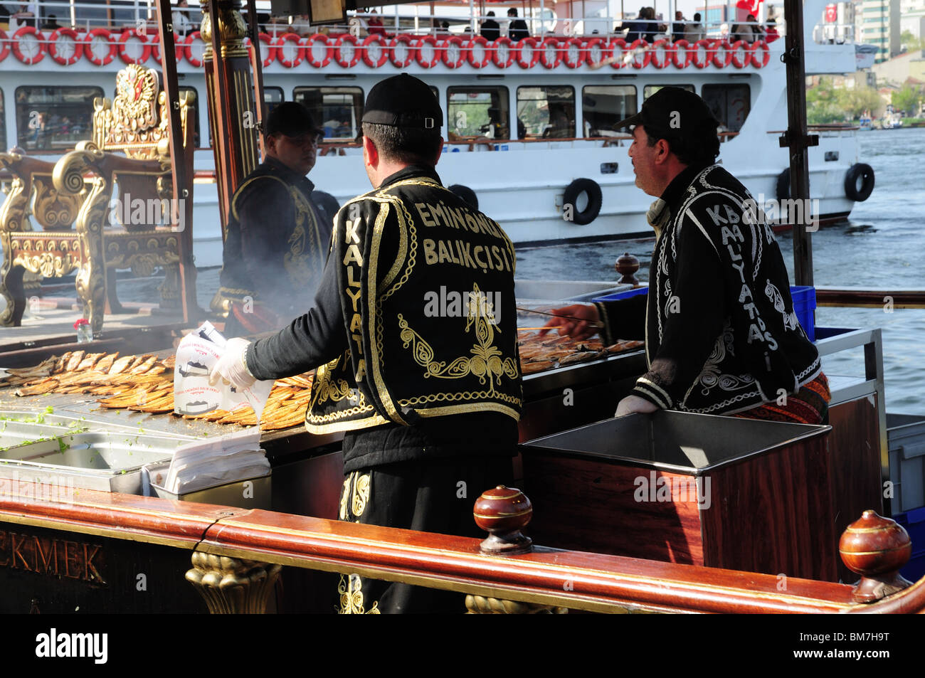 Preparare il pesce alla griglia di panini o Balik Ekmek su oro dipinto Barche Isola Eminonu Istanbul Asia Minore Foto Stock