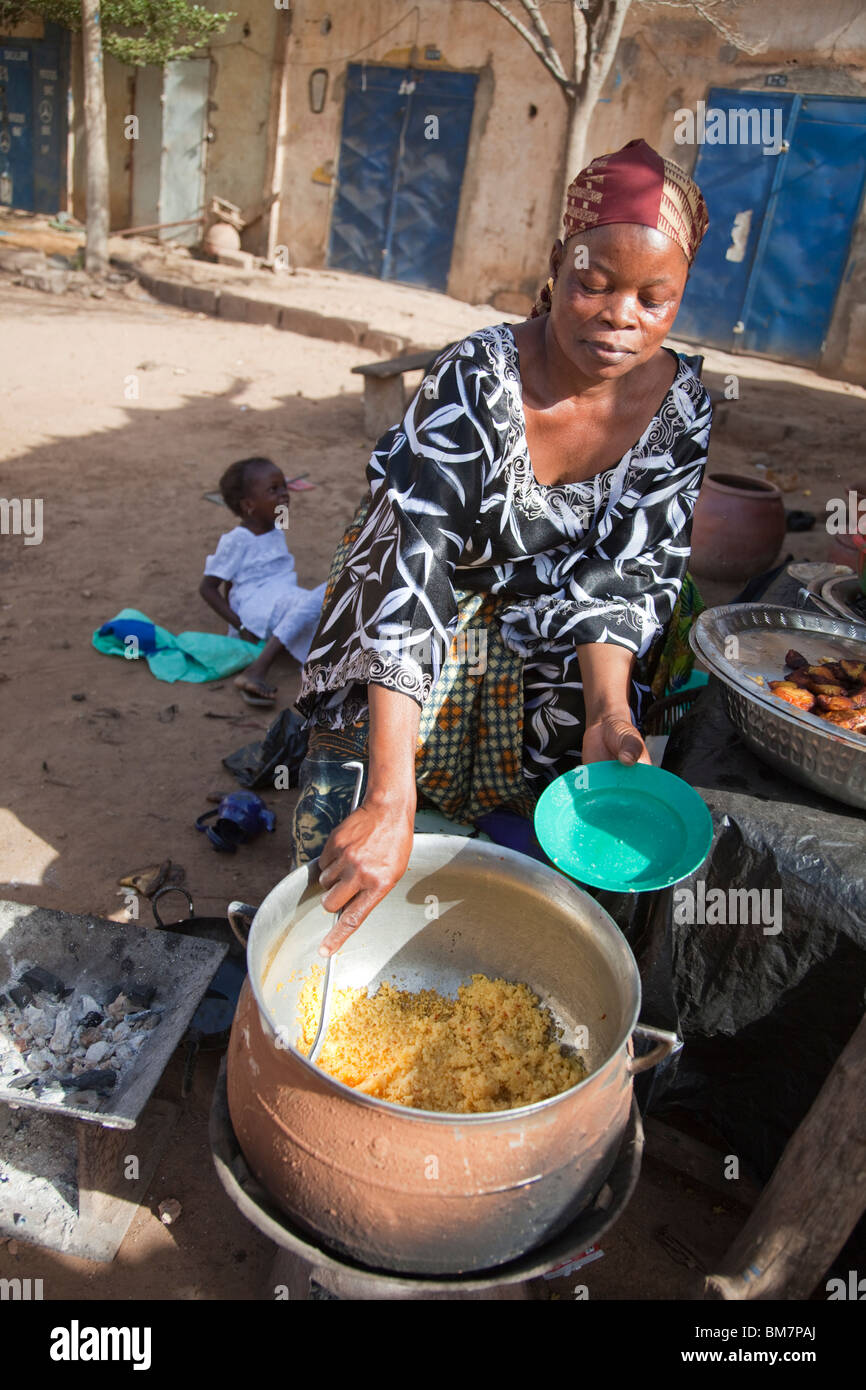 Una donna vende la frittura di banane da cuocere (alloco) e patate per la colazione vicino alla stazione degli autobus di Segou, Mali. Foto Stock