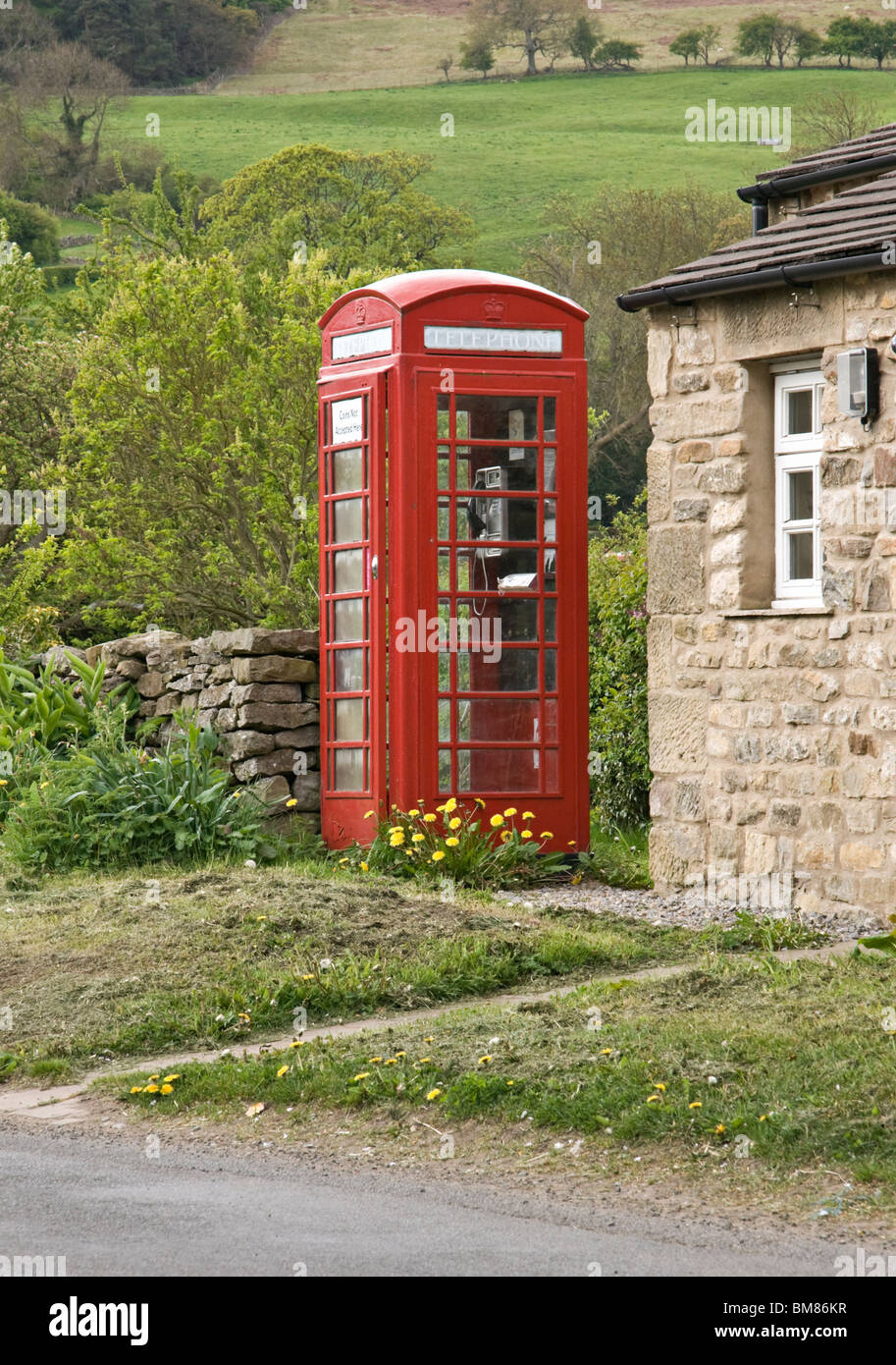 Telefono rosso casella al di fuori della sala di villaggio in villaggio di Oriente Witton, Wensleydale, Yorkshire Dales, North Yorkshire Foto Stock