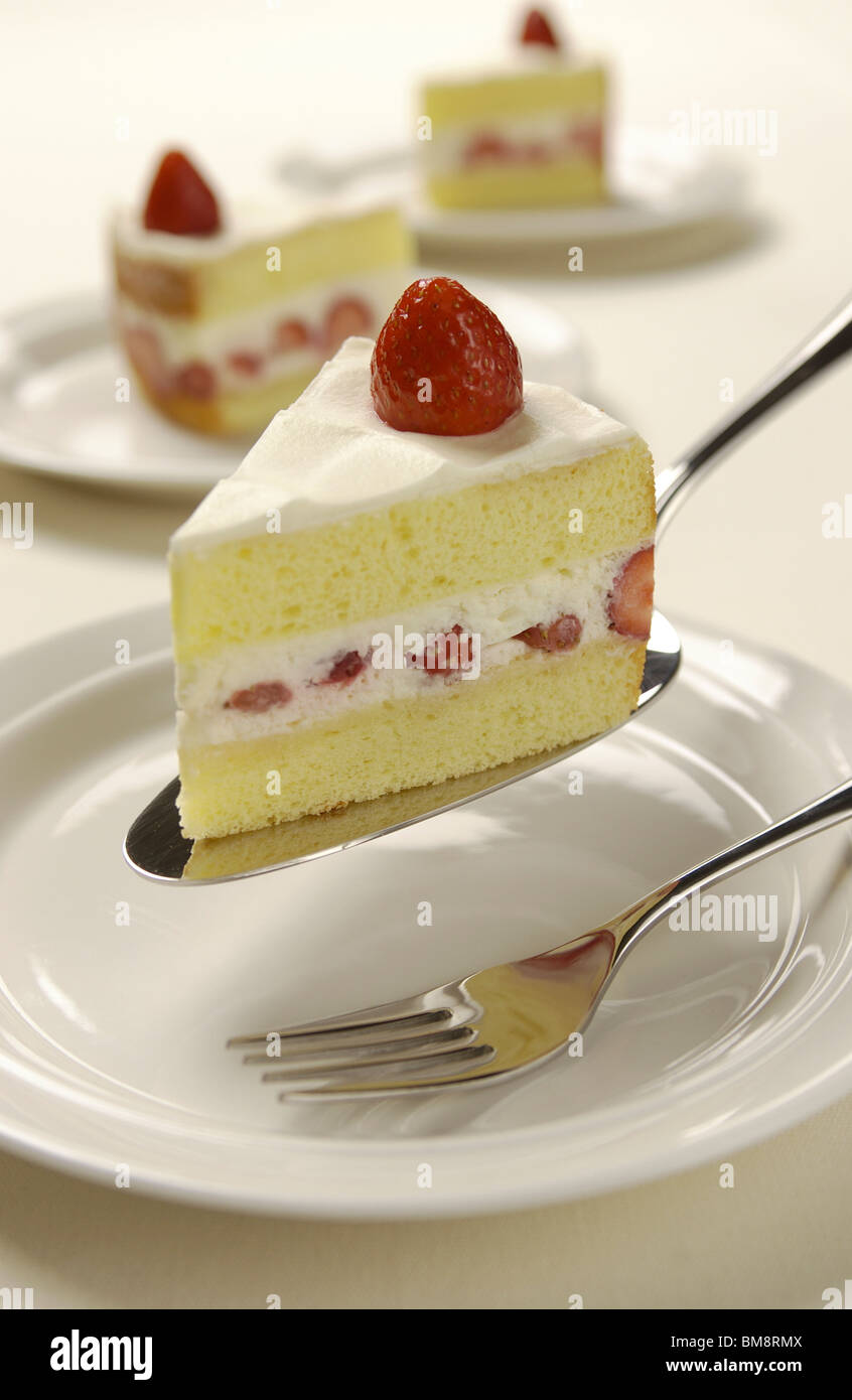 Fette di torta di fragole su server, sfondo bianco Foto Stock