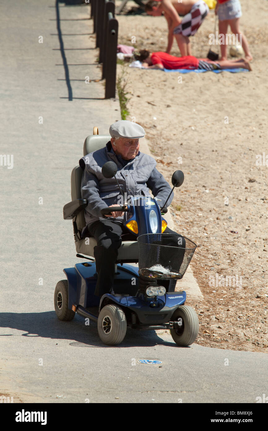 Il vecchio gentleman sui disabili motorizzata carrello scendendo la rampa verso la spiaggia Foto Stock