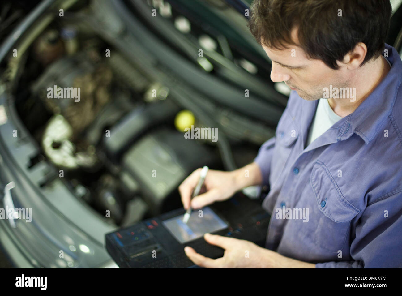 Mechanic utilizzando gli strumenti elettronici per la valutazione delle prestazioni delle automobili Foto Stock