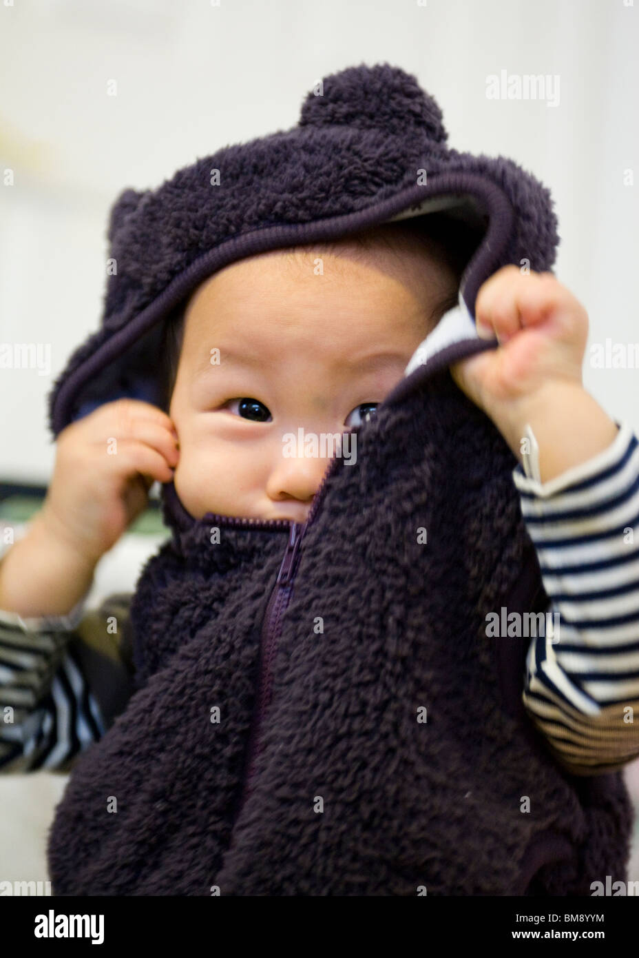 Asian baby boy rimuovendo la sua giacca Foto Stock