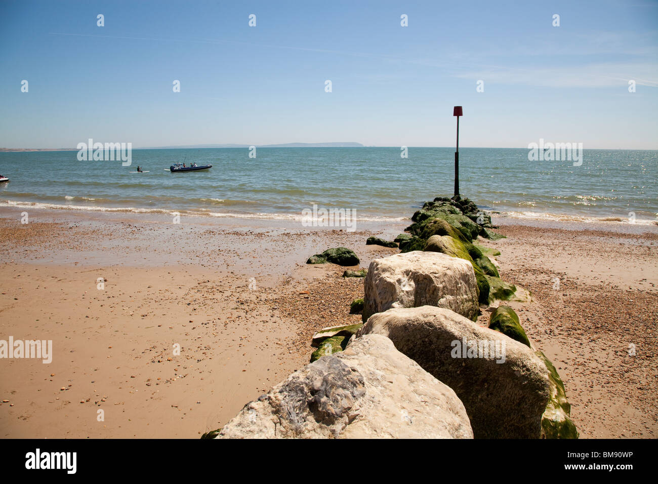 Le alghe coperto groyne in pietra in montagna con contrassegno rosso polo sulla spiaggia Muneford Foto Stock