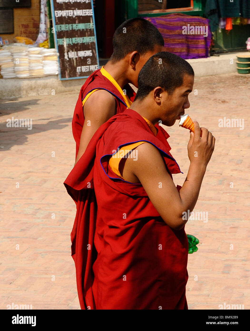 Due monaci buddisti tibetani , uno a mangiare il gelato,a boudhanath ,uno del santissimo siti buddista a Kathmandu in Nepal Foto Stock