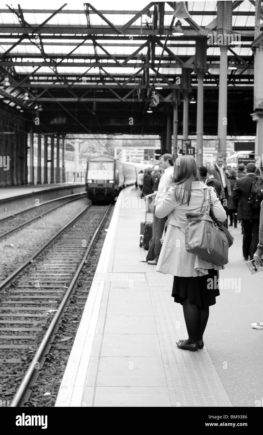 Una folla di persone in attesa sulla piattaforma del treno, girato in bianco e nero Foto Stock