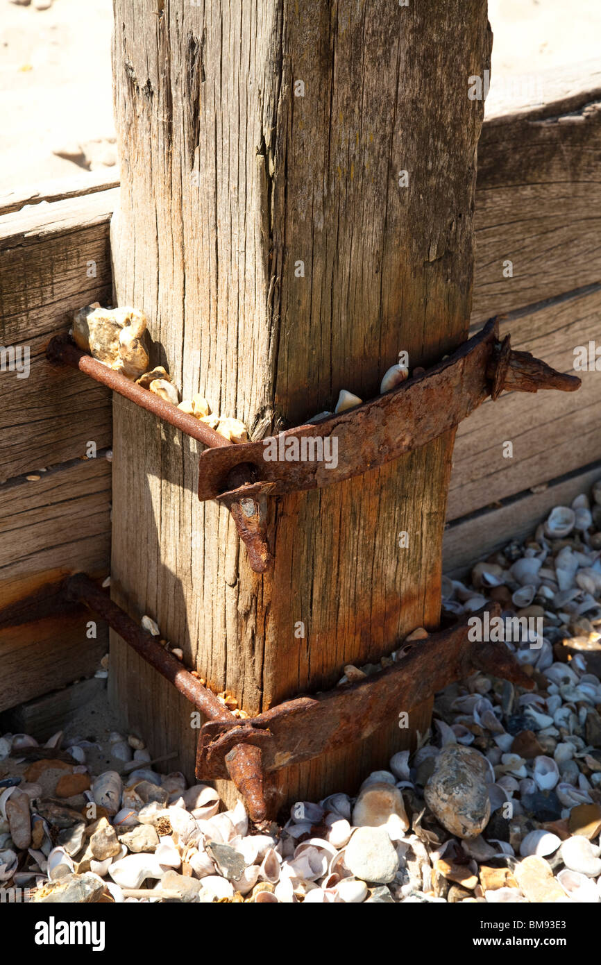 Arrugginimento fascetta metallica azienda groyne in legno al montante sulla spiaggia Foto Stock