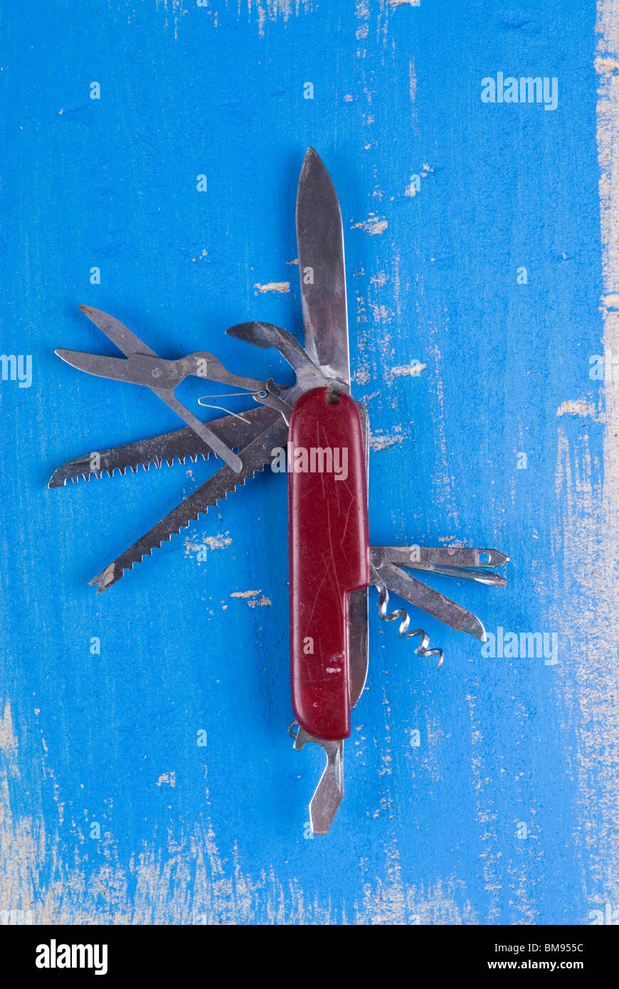 Vecchio coltellino svizzero su una superficie strutturata blu sullo sfondo di legno Foto Stock