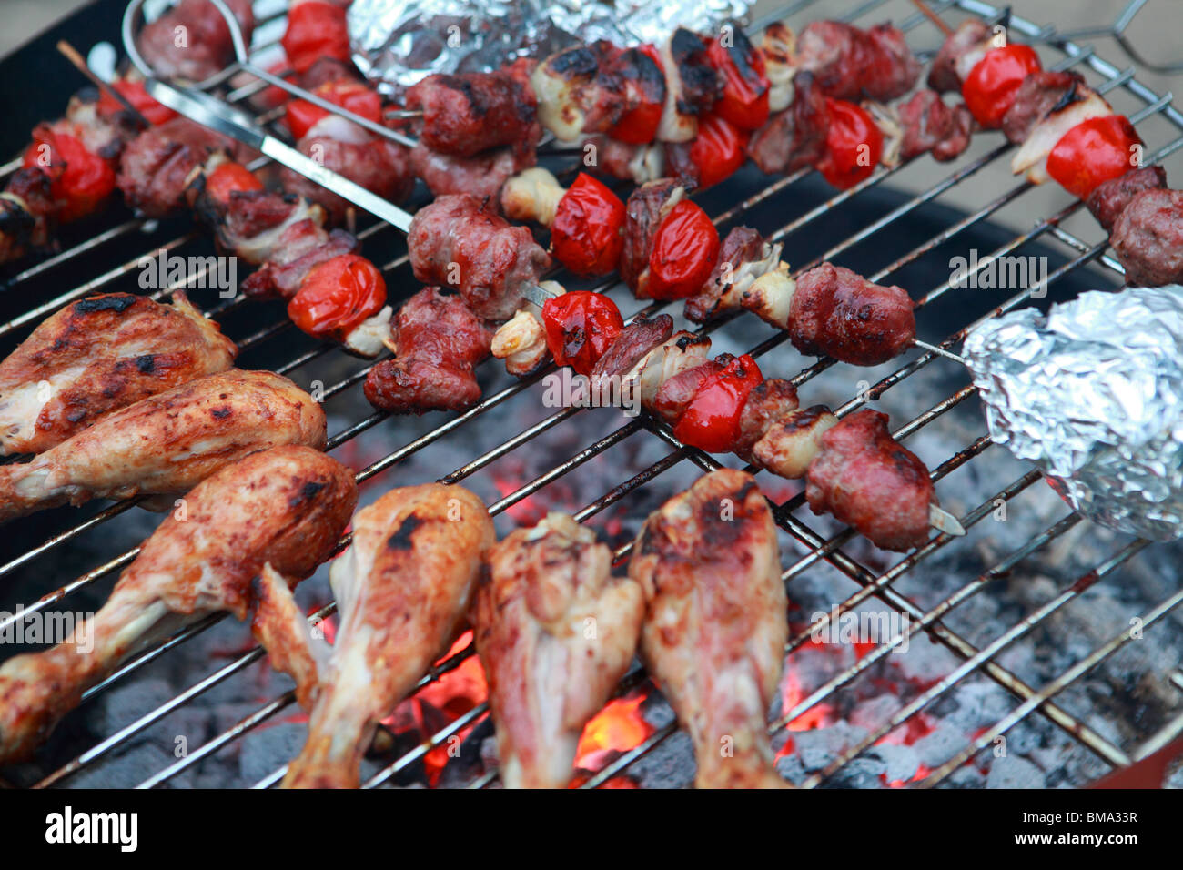 Cosce di pollo e spiedini cottura su un barbecue Foto Stock