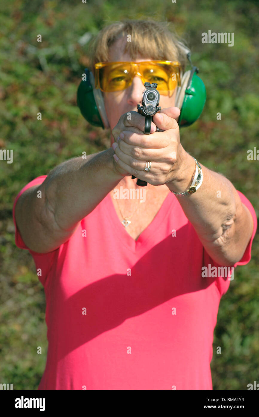 La donna prende la mira con la pistola al poligono di tiro. Foto Stock