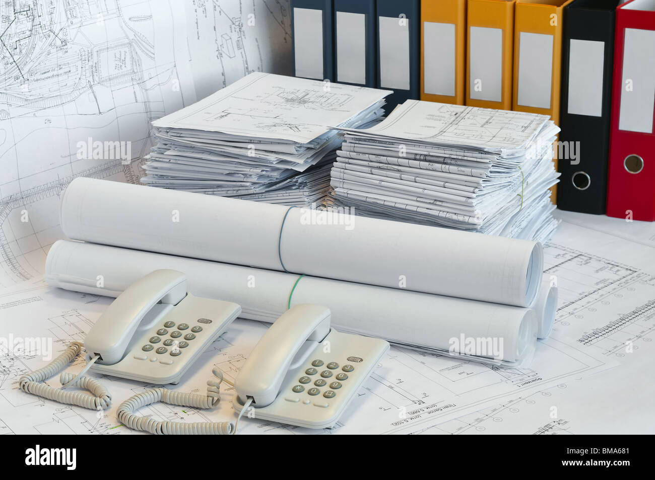 Grandi mucchi di progettazione e disegni, cartella e due telefoni sulla superficie del tavolo. White whatman sono lo sfondo. Foto Stock