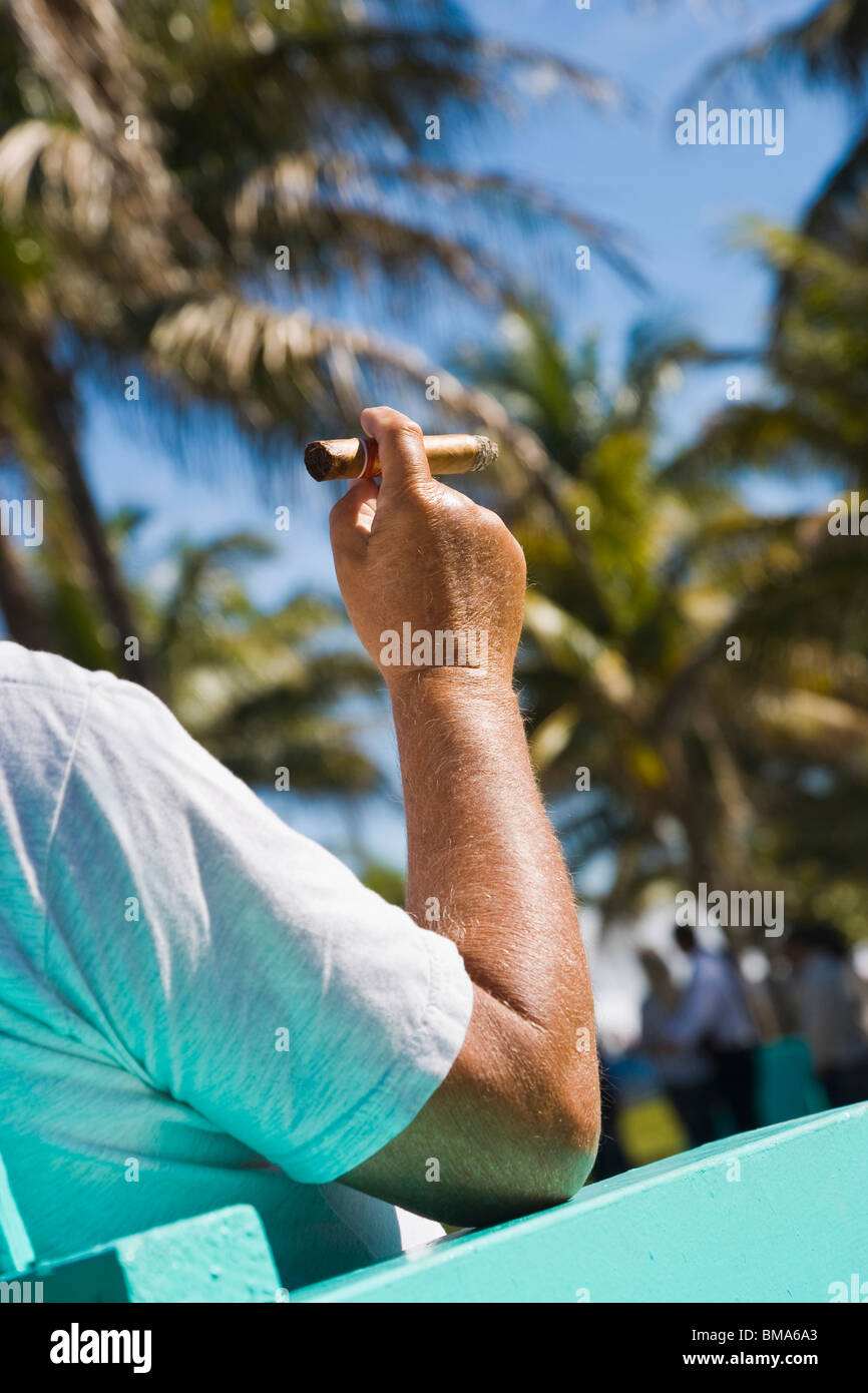 Uomo seduto su una sedia per esterno di fumare un sigaro, South Beach, Florida, Stati Uniti d'America Foto Stock