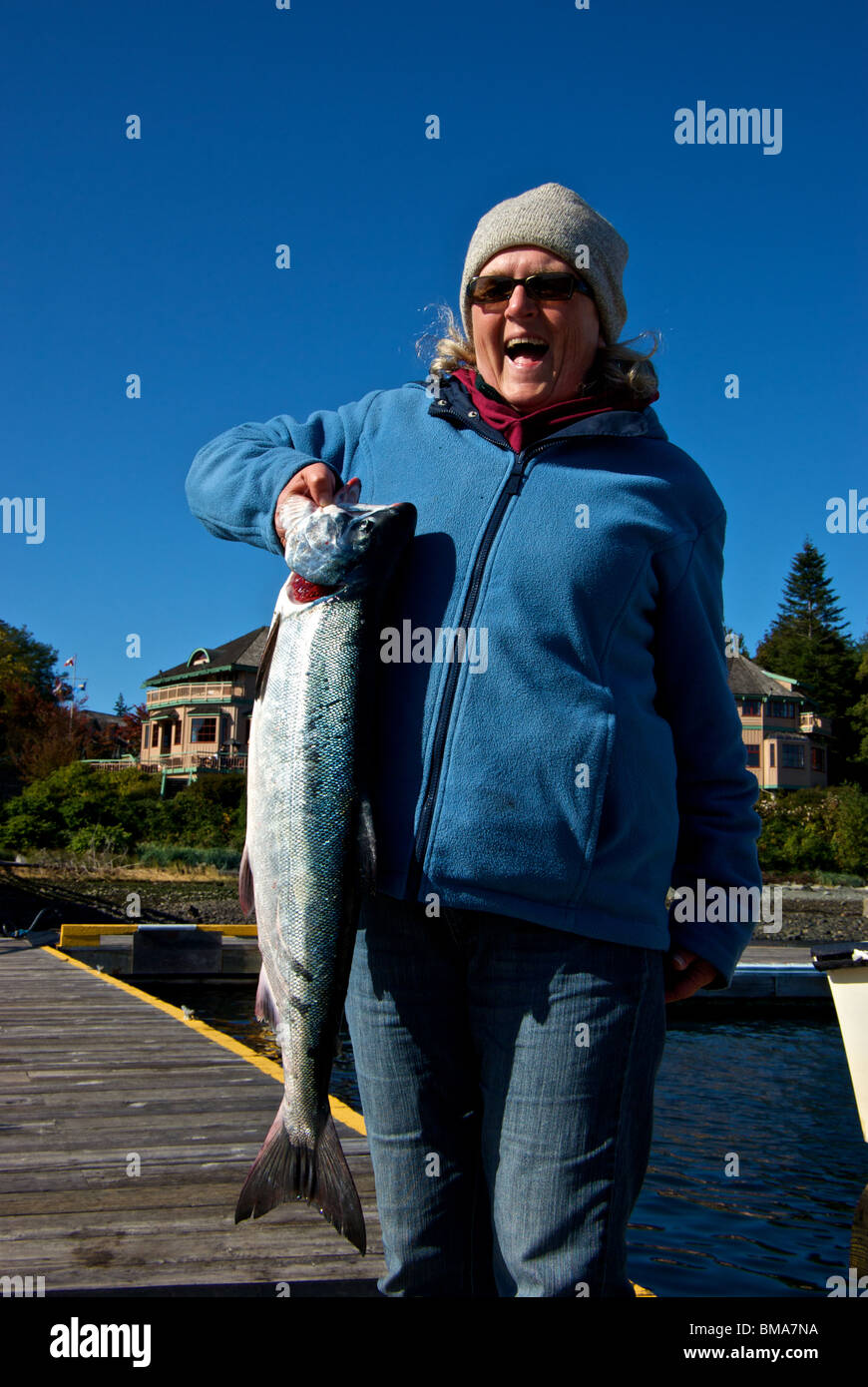 Felice pescatore femmina mentre tiene il suo primo autunno chum Salmoni (Oncorhynchus keta) Foto Stock