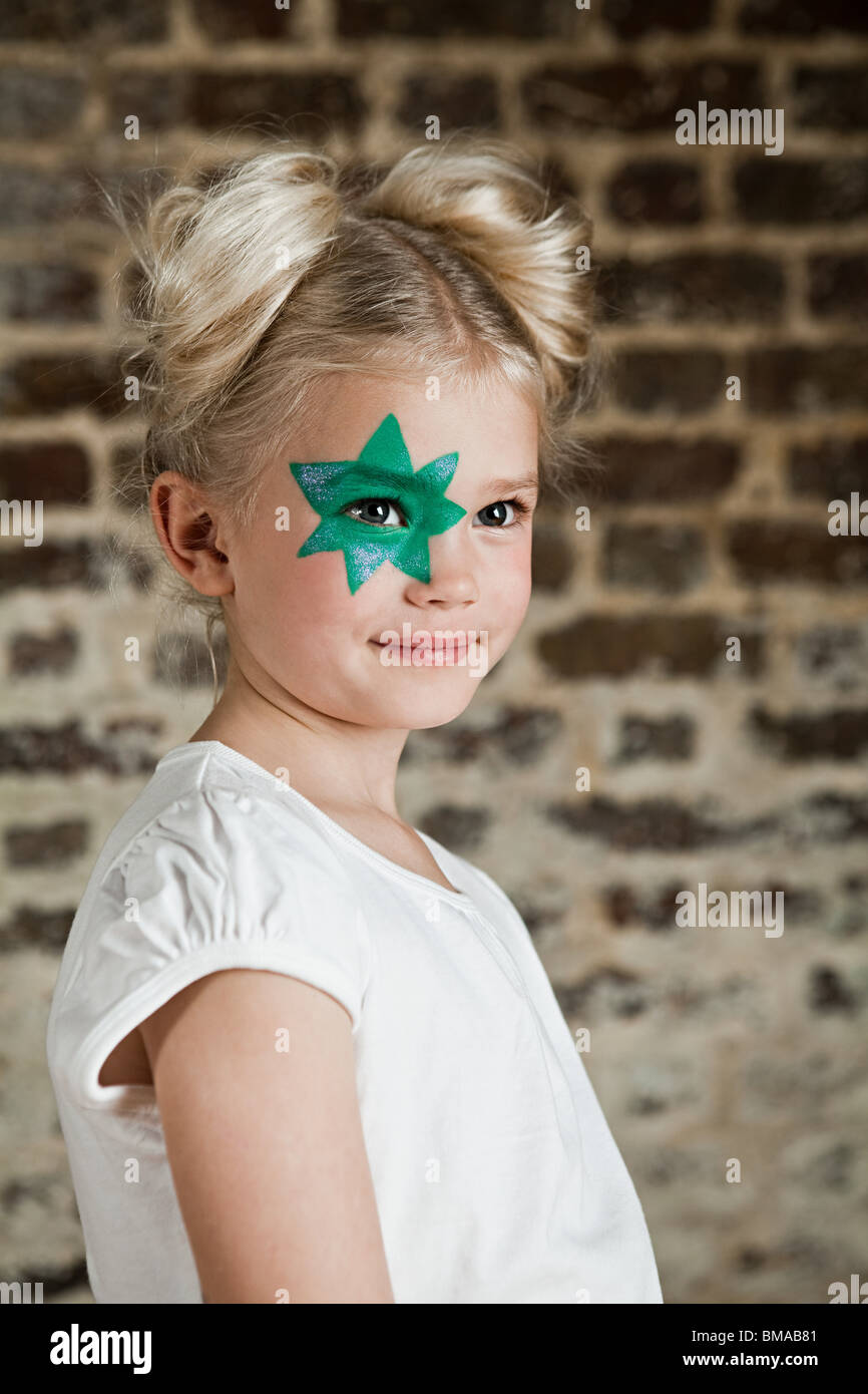 Ragazza giovane con la stella verde face paint over eye Foto Stock