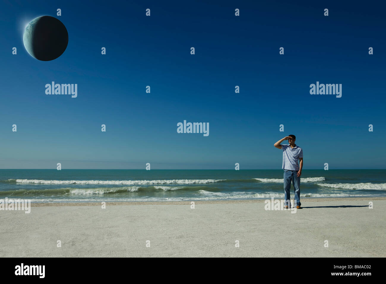 Uomo sulla spiaggia osservando eclipse Foto Stock